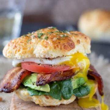 Ultimate Breakfast Sandwich- Fresh baked cheddar bay biscuits (low-fat and ready in 15 min.) take this breakfast sandwich to a whole new level! Topped with a poached egg , crispy bacon and healthy veggies like spinach, avocado and tomato