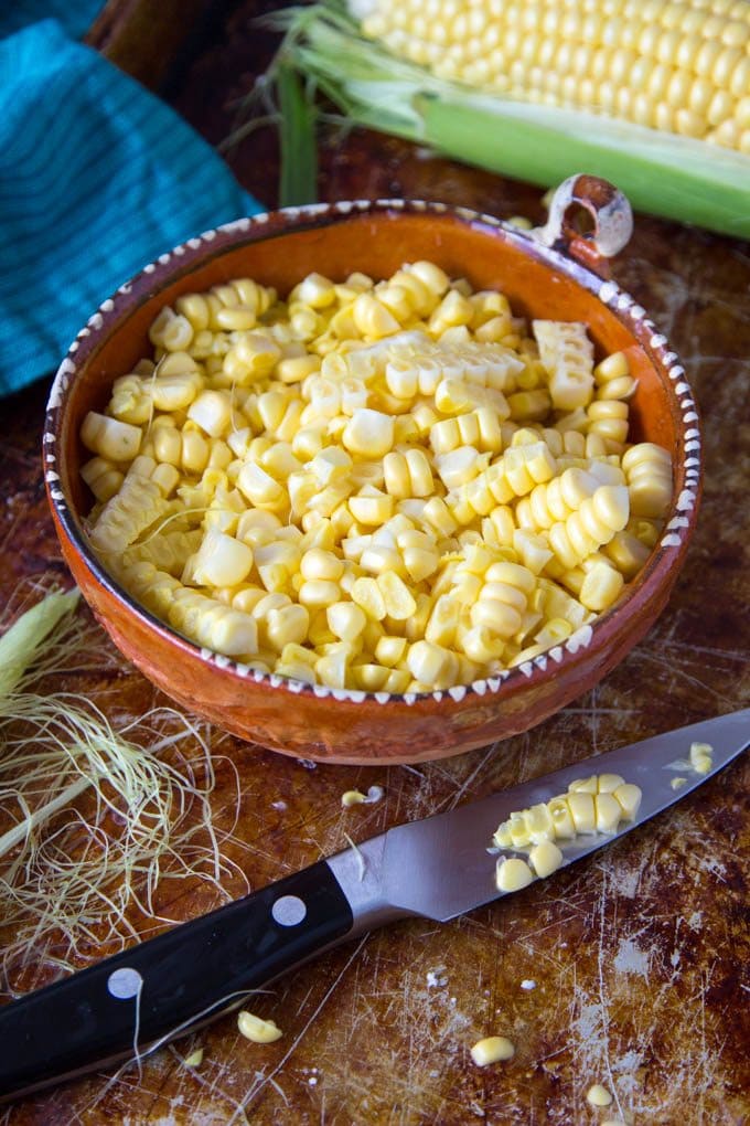 Corn kernels cut from corn cob in a terra cotta bowl