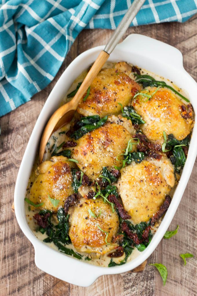 Chicken with Creamy Sun Dried Tomato Sauce + Spinach- Super Easy! Chicken thighs are smothered in a "to die for"creamy Sun Dried Tomato and Parmesan sauce and baked to golden brown perfection. It's easy, it's comforting, and it's only about 330 calories per serving.