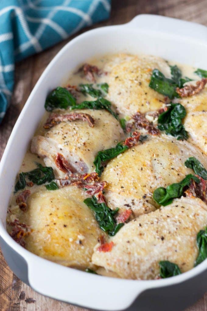 Chicken with Creamy Sun Dried Tomato Sauce + Spinach- Super Easy! Chicken thighs are smothered in a "to die for"creamy Sun Dried Tomato and Parmesan sauce and baked to golden brown perfection. It's easy, it's comforting, and it's only about 330 calories per serving.