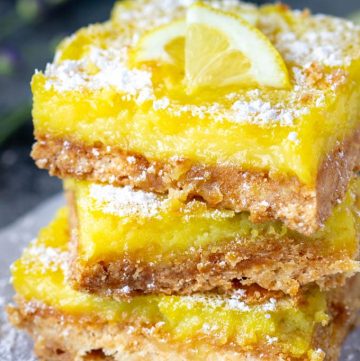 3 lemon bars stacked on top of one another and dusted with powdered sugar
