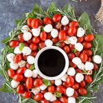 Caprese Salad Appetizer Christmas Wreath Appetizer -the wreath -mozzarella balls and grape tomatoes are on a platter in the shape of a wreath