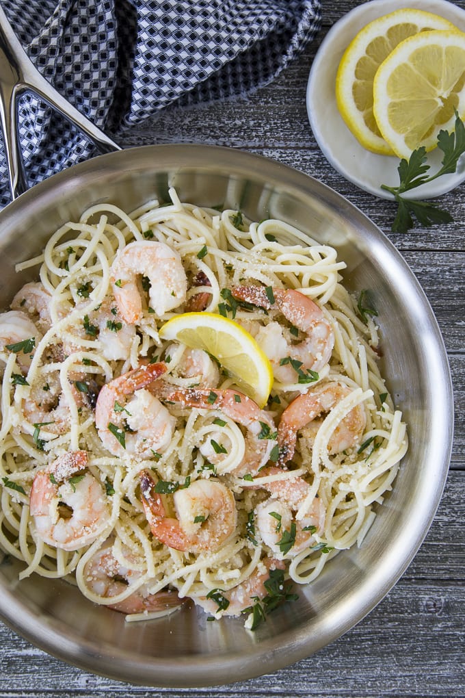 Shrimp scampi - cooked shrimp in a garlic butter sauce over cooked spaghetti noodles in a silver skillet