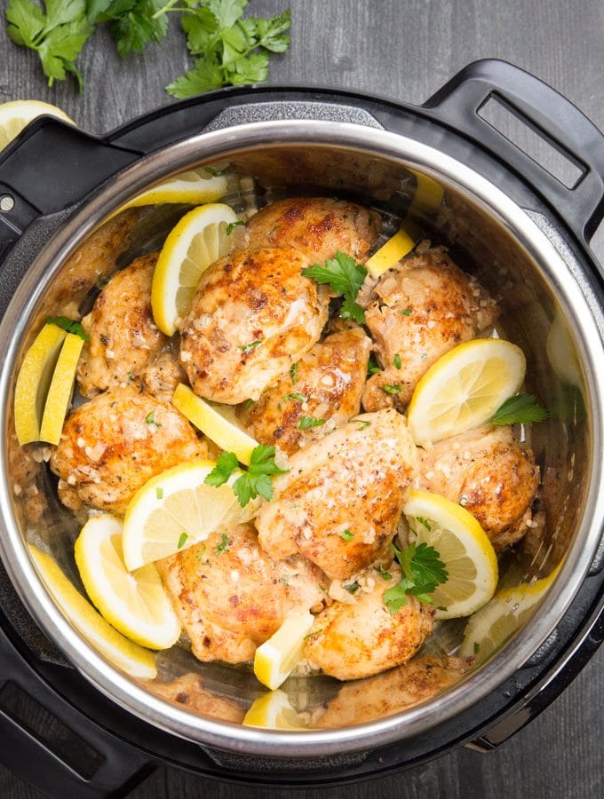 cooked chicken thighs in the Instant Pot with lemon slices and fresh parsley