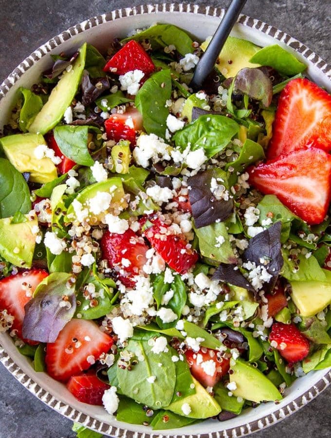 spinach salad with quinoa strawberries and feta up close in a white bowl