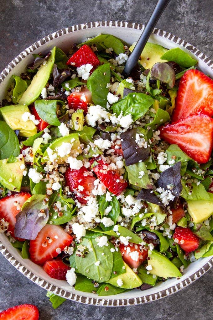 up close view of Spinach Salad with strawberries, quinoa, feta, avocado, and basil in a white bowl